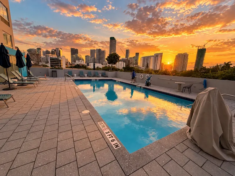 Rooftop pool at sunset with the Miami skyline, serviced by our team